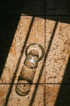 Empty drinking glass on the floor casting shadow Stock Photos