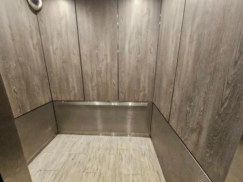 Empty Elevator Cab With Wood Grain Panels and Stone Tile Floor 스톡 사진