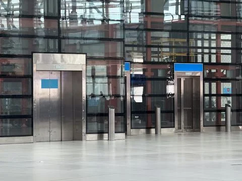Empty elevator entrances aligned inside modern airport terminal wall. Vertica Stock Photos