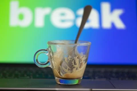 Empty espresso cup on laptop keyboard with break text background Stock Photos