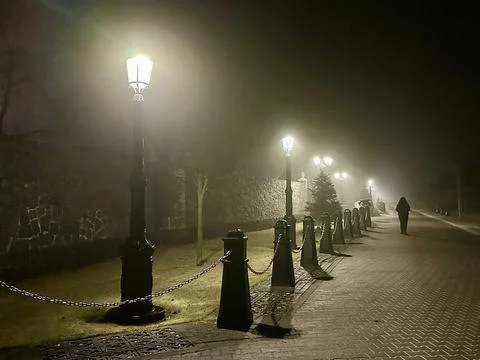 An empty evening street glows softly under warm street lights, creating a s.. Stock Photos