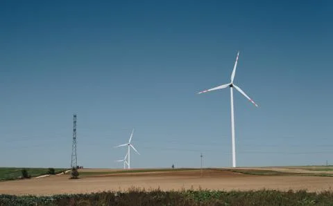 Empty fields and wind turbines over clear blue sky Stock Photos