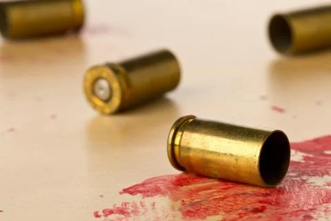 Empty, fired, blood covered 9mm bullet casings on wood floor background at CS Stock Photos