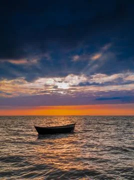 Empty fishing boat in the rays of the setting sun. Stock Photos