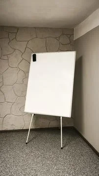 Empty flipchart board set up in classroom with stone wall background. Stock Photos