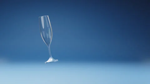 Empty Flute Glass Spinning on Studio Blue Background Stock Footage 241829059