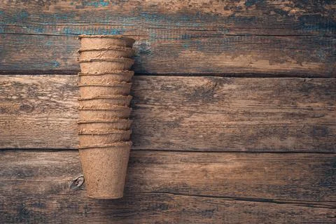 Empty, folded peat cups for seedlings on a brown background. Stock Photos