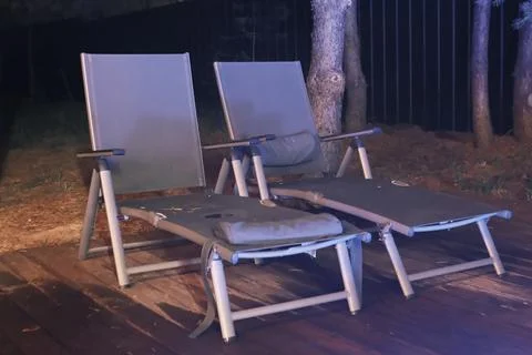 Empty folding lounge chairs placed on a wooden deck during the night Photos