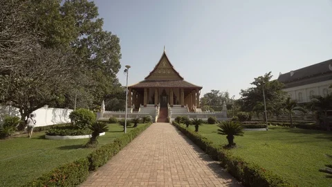 Empty footpath amidst plants leading towards famous museum against sky on sunny Stock Footage 129210535