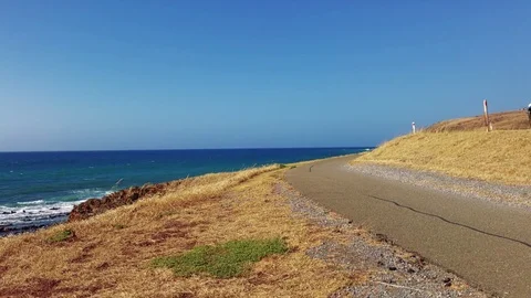 Empty footpath curving around coast ocean headland with car driving past in 4k Stock Footage 71317003