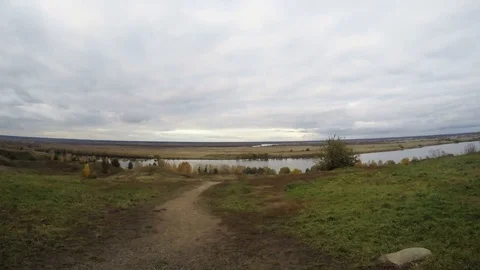 Empty footpath on high bank of river on cloudy autumn day rural area. Aerial Stock Footage 81672725