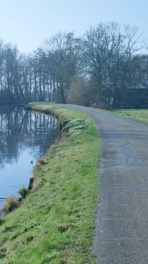 Empty footpath running along a tranquil riverbend Vidéo 334424888