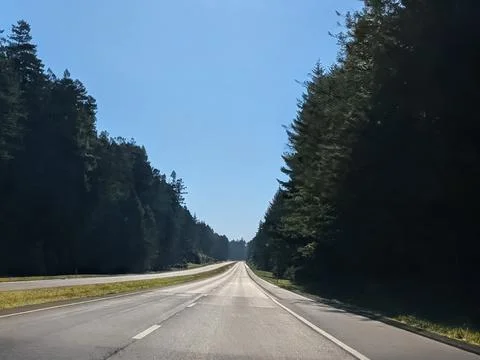 Empty four-lane highway divided by grassy median stretches Stock Photos