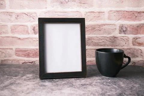 Empty frame and a coffee mug on wooden background . Stock Photos