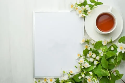 Empty frame with flowers and a cup of tea on a light background. It is possib Stock Photos