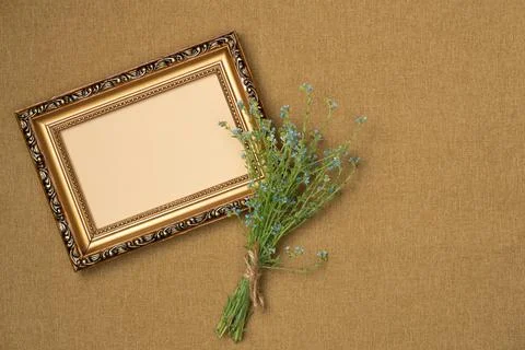 Empty frame with flowers on fabric background from above. Vintage style. To.. Stock Photos