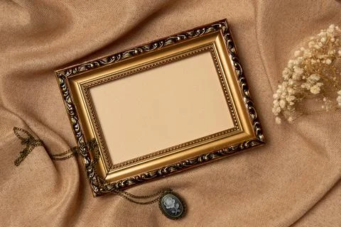 Empty frame with old medallion and flower on a fabric background from above.. Stock Photos