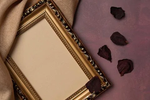 Empty frame with rose petals and fabric on a burgundy background from above.. Stock Photos