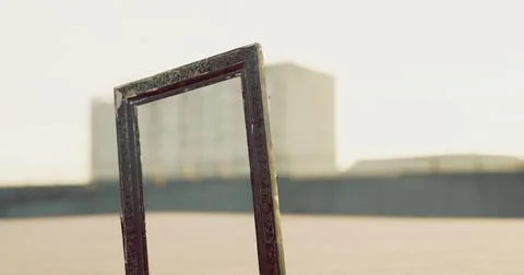 Empty frame standing against a background of distant buildings at sunrise Ilustración de archivo