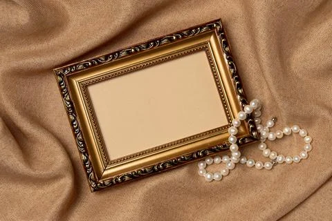 Empty frame with string of pearls on a fabric background from above. Vintage  Stock Photos