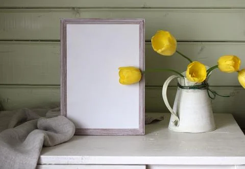 Empty frame on the table and yellow tulips, rural spring mockup. copy space. Foto stock