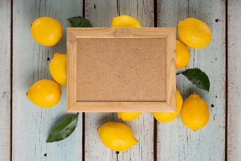 Empty frame for text with lemons and green leaves, top view Stock Photos