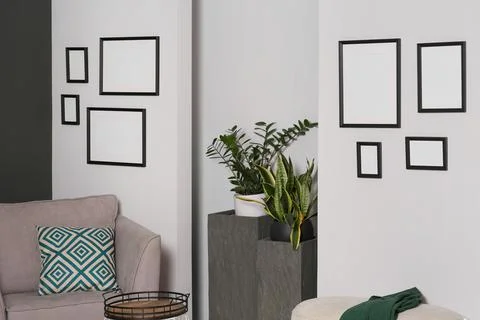 Empty frames hanging on white wall in stylish room Foto stock