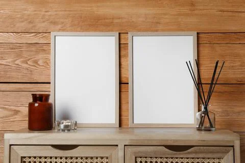 Empty frames with other decor on table near wooden wall. Mockup for design Stock Photos