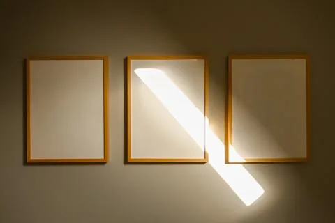 Empty frames on wall with golden sunlight shining through art gallery desig.. Stock Photos