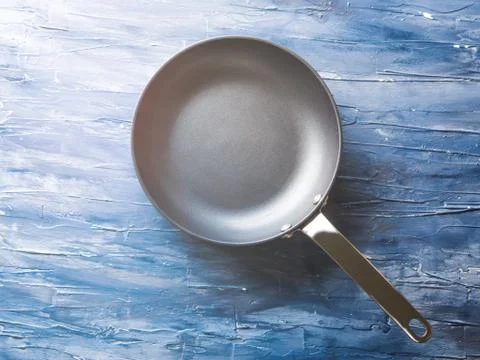 Empty frying pan on blue background. Stock Photos