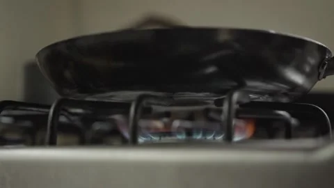 Empty frying pan heating over an active gas burner with visible blue flame in a Video stock 334629478