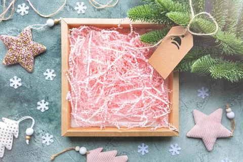 Empty gift box with pink paper filling on green background with Christmas decor. Stock Illustration