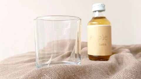 An empty glass and a bottle of apple soda with white background Stock Footage 145462757