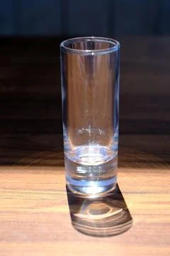 Empty glass and its shadow on a wooden table Stock Photos