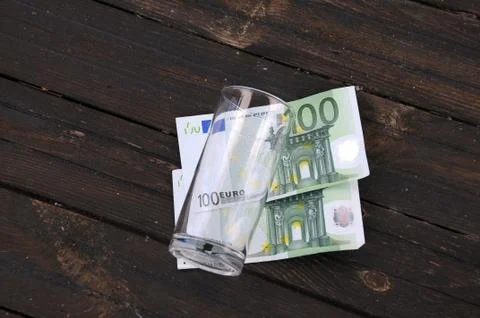 Empty glass and two one hundred euro banknotes Stock Photos