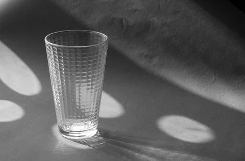Empty glass beaker on a gray surface with shadows. Foto stock