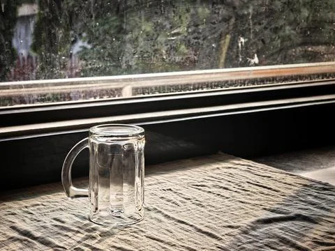 Empty glass beer mug on a checkered tablecloth by the window under warm sunlight Stock Photos