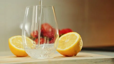 Empty glass between two part of cut lemon on wooden cutting board Stock Footage 143402447