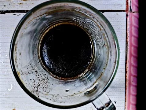 Empty glass of black coffee on a table with leftover coffee stains. Stock Photos