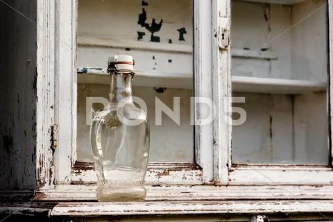 Empty glass bottle on an old kitchen cabinet Stock Photos