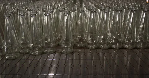 Empty glass bottles aligned on a conveyor belt at an industrial bottling plant Stock Footage 303107696