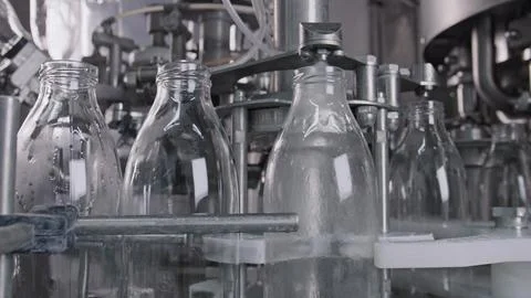 Empty glass bottles moving along conveyor belt in dairy plant Stock Illustration