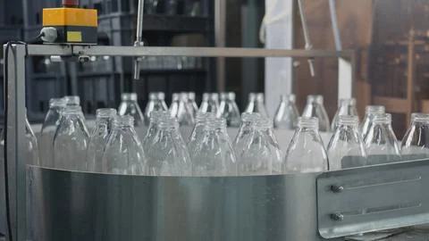 Empty glass bottles moving on conveyor belt in dairy plant Stock Illustration