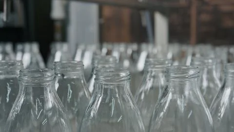 Empty glass bottles moving on conveyor belt in dairy plant Stock Illustration