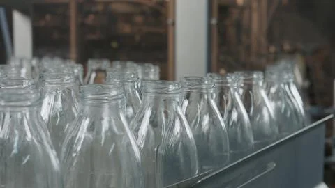 Empty glass bottles moving on conveyor belt in dairy factory Stock Illustration