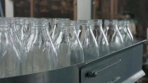 Empty glass bottles moving on conveyor belt in dairy factory Stock Illustration