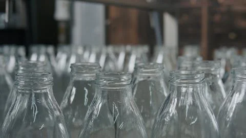 Empty glass bottles passing on conveyor belt in dairy plant Stock Illustration