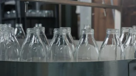 Empty glass bottles passing on industrial conveyor belt Stock Illustration