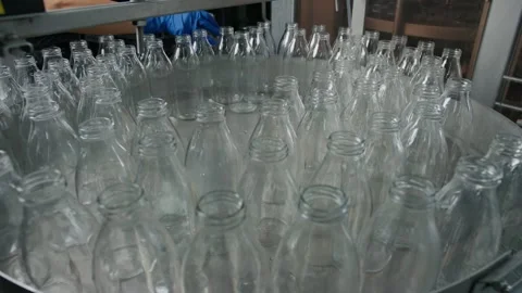 Empty glass bottles rotating on a metal platform in a dairy factory Stock Footage 313547230