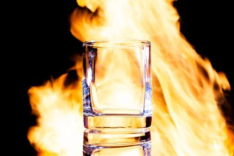 Empty glass of brandy against the background of fire, place under the text Stock Photos